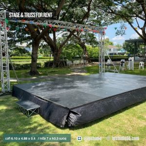 มุมเฉียงเวทีกลางแจ้งขนาด 6.10 x 4.88 เมตร พร้อมทรัสประดับไฟและธงสี บรรยากาศร่มรื่นในสวน