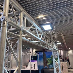 ไฟสปอร์ตไลท์ติดตั้งบนโครงทรัสอลูมิเนียมในงานจัดแสดงสินค้า ให้แสงสว่างครอบคลุมพื้นที่โดยทีมงาน IP Studio55 บริการเช่าไฟสปอร์ตไลท์คุณภาพสูง